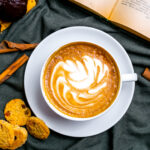 top view cup of cappuccino with cookies and a book on the table
